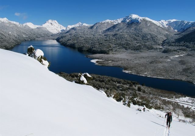 Julian Casanova subiendo por la senda clasica con nieve desde la ruta, lago Villarino y el cajon negro de fondo.